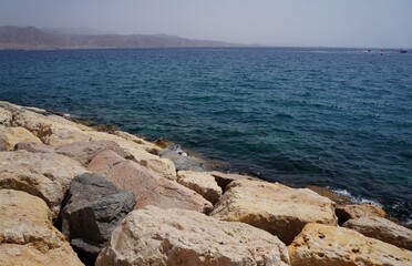 Fototapeta na wymiar Clear sea water surface, stones and glare
