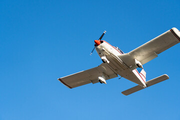 Small plane flying in a clear blue sky turning to land
