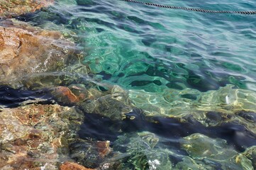 Clear sea water surface, stones and glare