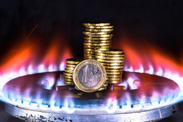 A euro coin closeup along with a row of yellow coins on a gas burner against a blue flame of...