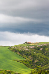 Farm on a hill with fields and dark storm clouds