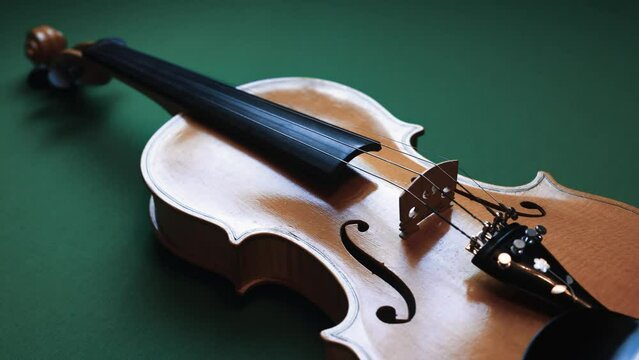 An beige violin from above. Dolly shot. Isolated with green background.