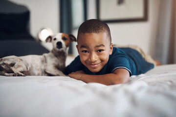 Chilling with my home dog. Shot of an adorable little boy playing with his pet dog on the bed at...