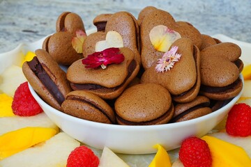 Heart shaped chocolate macaron cookies with pressed edible flowers for Valentines Day