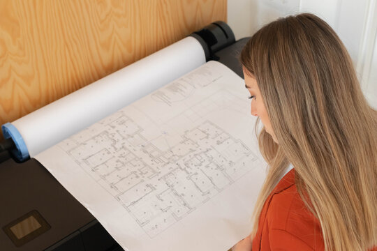 Interior design woman printing in plotter large blueprints and floor plans