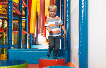 Child having fun on modern playground. Happy little boy playing in indoor playground on jumping...