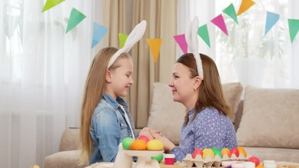 mom and daughter with rabbit ears celebrate Easter and cuddle and kiss 