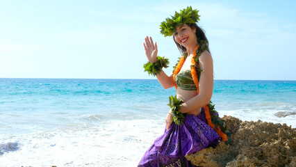 Young lady shakes hand saying hello pretty smiling posing in bikini on the beach. Smiling woman receives waving hand. Exotic beauty. Hawaiian typical costume.