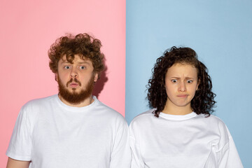 Half length portrait of young emotive man and girl making faces isolated on blue and pink trendy...