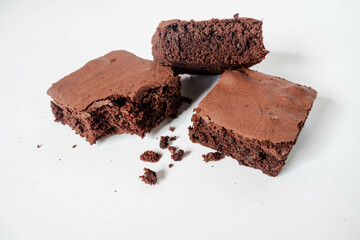 Pieces of homemade chocolate brownies with crumbs on white background.