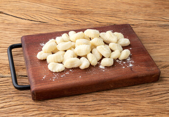 Uncooked italian pasta gnocchi on a board over wooden table