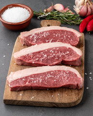 Sliced raw picanha or rump meat over wooden board with seasonings