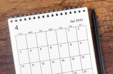 April 2022 desk calendar on wooden table.