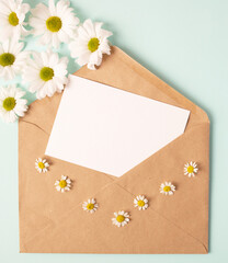 Greeting card concept for valentine's day, wedding or mother's day, women's day. Open envelope with blank sheet of paper and beautiful red cute paper hearts, chamomile on blue, mint background
