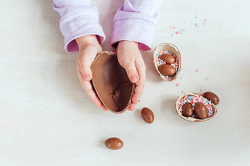 Little girl holds a chocolate Easter egg in her hand. Close up. Happy easter