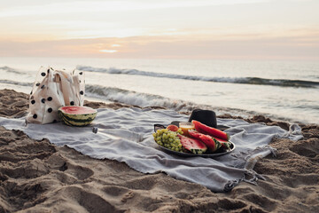 Picnic Set with Fruits by the Sea at Early Morning, Preparing to Sunrise on Sandy Beach