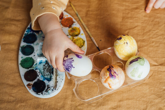 A child paints Easter eggs with colors
