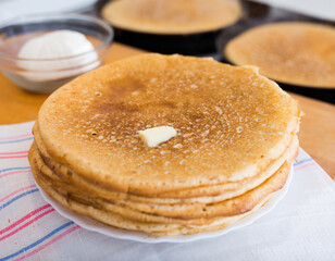 freshly baked hot cereal pancakes on plate and pans during cooking