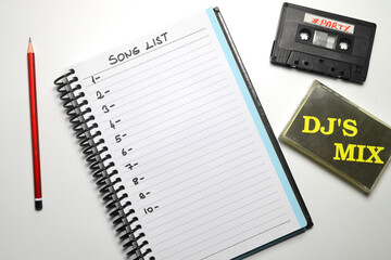 Retro audio cassette tape from the 80s and 90s on a white background. blank playlist on notebook. Top view, nostalgic concept.