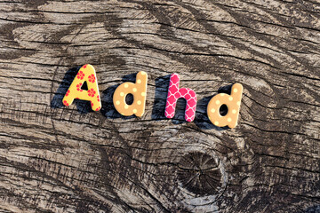 Letters ADHD written on colorful toy text on wooden surface. Attention deficit hyperactivity disorder concept. - obrazy, fototapety, plakaty
