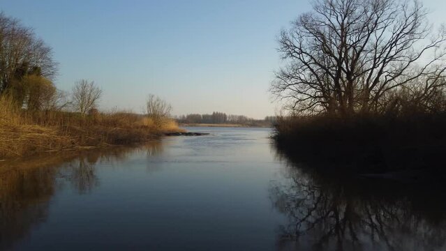 Narrow side stream culminating in river Scheldt, aerial fly forward view