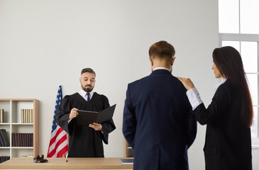 Lawyer and client listen to male judge make verdict in court of United States of America. Attorney...