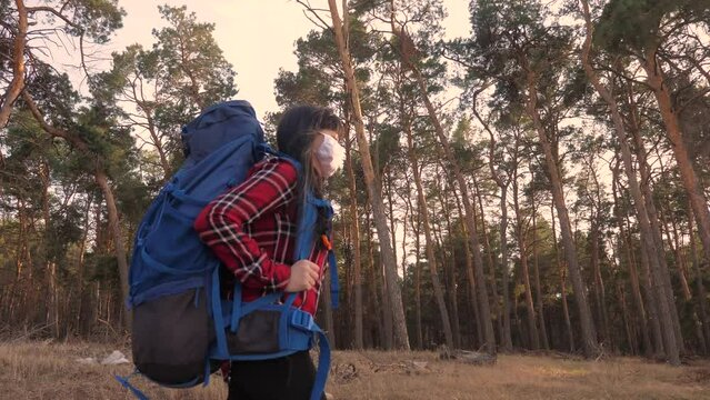 tourist hiker girl goes for a walk near a hiking backpack forest park. concept pandemic virus lifestyle epidemic world catastrophe infection covid