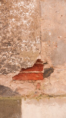 Ladrillo rojo asomando en pared vieja de estuco