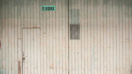 Cartel de "SE ALQUILA" en puerta de madera rústica de garage