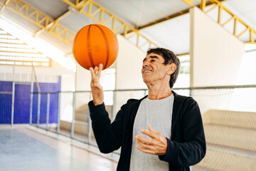 Physical activity in old age. 70s man playing basketball. Latino elderly practicing physical...