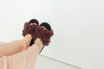 Young woman in soft cozy brown slippers resting at home