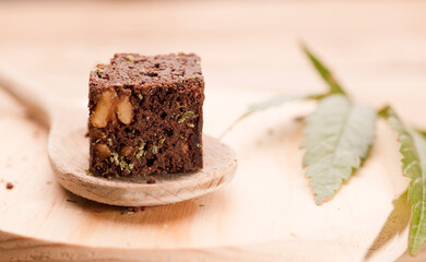 piece of brownie with marijuana, on wooden spoon and green cannabis leaf
