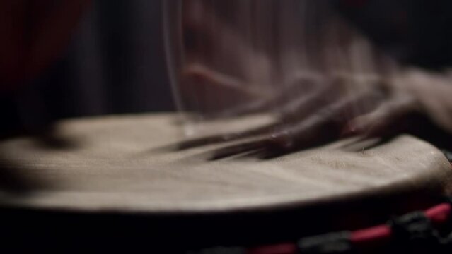 Closeup of hands black man playing an african folk drum, dark background in studio. Black man plays bongo drum. Concept of folk ethnic music