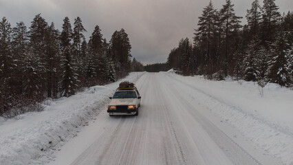 Old car in the swedish snowy roads between the forests. Car driv