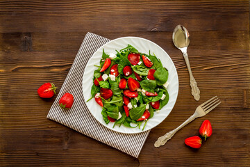 Green spinach salad with red strawberry and goat cheese, top view