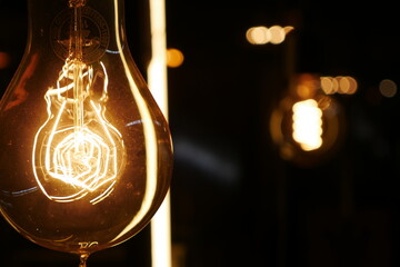 Vintage old light bulb glowing yellow on  dark background 
