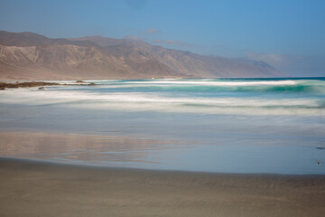 Long exposure image of a landscape with beach, sea and mountains at the Pacific coast of nortwest Chile
