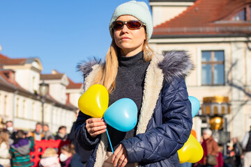 A girl at a rally for Ukraine in Germany with a poster of no war and balloons in the color of the...