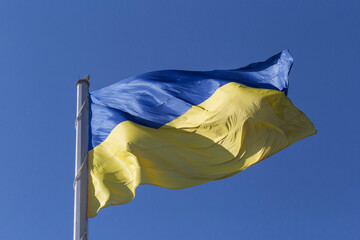 Ukrainian flag on flagpole against clear blue sky