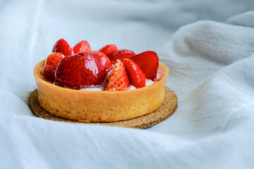 Birthday at home in bed alone. Lazy cozy holiday. Light airy gray neutral view. Bright tart with strawberries and butter cream on a textile, bakery, dessert. Simple template. Positive emotions, joy.