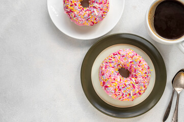 Pink donut with sprinkles on bright background, sweet food