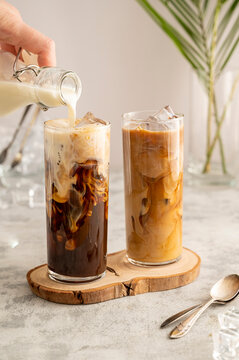 Iced coffee in glass. Pouring milk in glass with coffee. Summer drink.