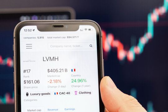 LVMH stock price on the screen of cell phone in mans hand with changing stock market exchange with trading candlestick graph analysis, February 2022, San Francisco, USA