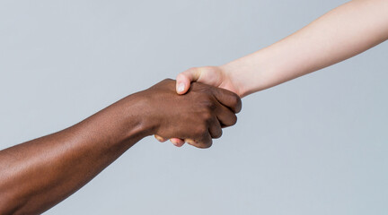 Black and white human hands. African and caucasian hands. Giving a helping hand to another. Woman...