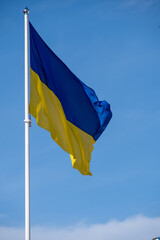 Ukrainian flag waving in the wind against a bright blue background