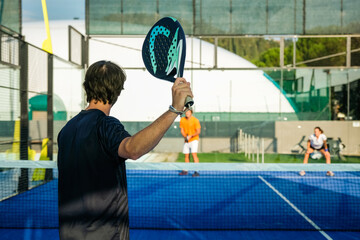 Mixed padel match in a blue grass padel court - .Beautiful girl and handsome man playing padel...