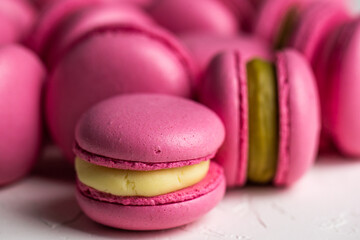Macarons closeup on white wooden background. Sweet and colourful pink french macaroons. Cooking at home.