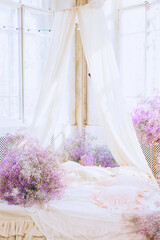 bed in bedroom in lilac tones very peri color of the year 2022 in boho style, butterfly and lilac gypsophila flowers, vintage decor in retro loft style room, celebrating Valentine's Day on February 14