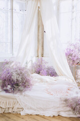 bed in bedroom in lilac tones very peri color of the year 2022 in boho style, butterfly and lilac gypsophila flowers, vintage decor in retro loft style room, celebrating Valentine's Day on February 14
