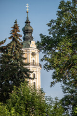 Fototapeta na wymiar Kloster Heilig Kreuz Kirchturm mit Dreierkreuz hinter Bäumen